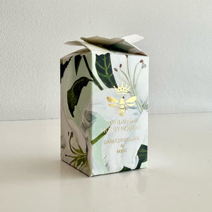 Honey nougat packaging with floral design and gold bee emblem on a white background