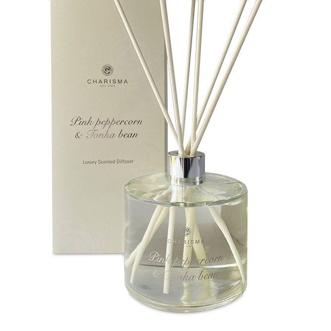 A clear glass diffuser bottle with pink peppercorn and tonka bean fragrance, featuring a label with the brand name Charisma Candles and the product name Pink Peppercorn & Tonka Bean - Luxury Scented Diffuser.
