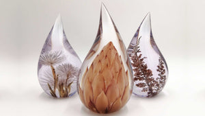 Three teardrop-shaped resin art pieces with natural foliage on a white background