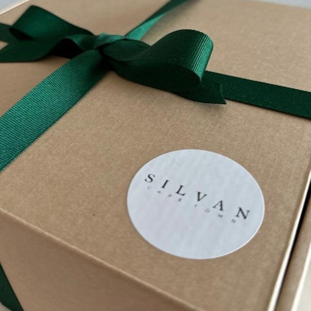 Gift box with a green ribbon and 'SILVAN' label on a beige background
