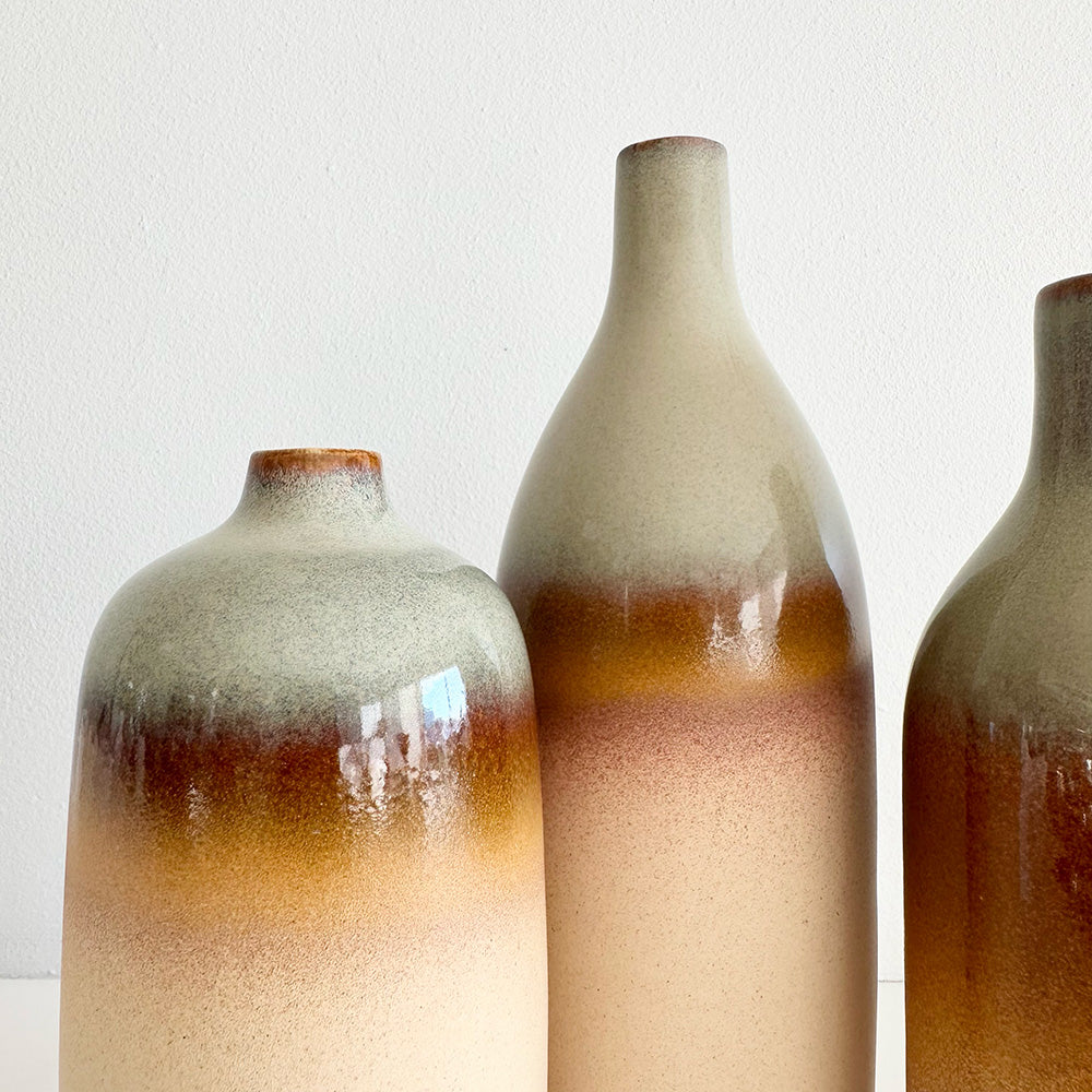Three ceramic bottles with gradient brown and beige colors on a white background