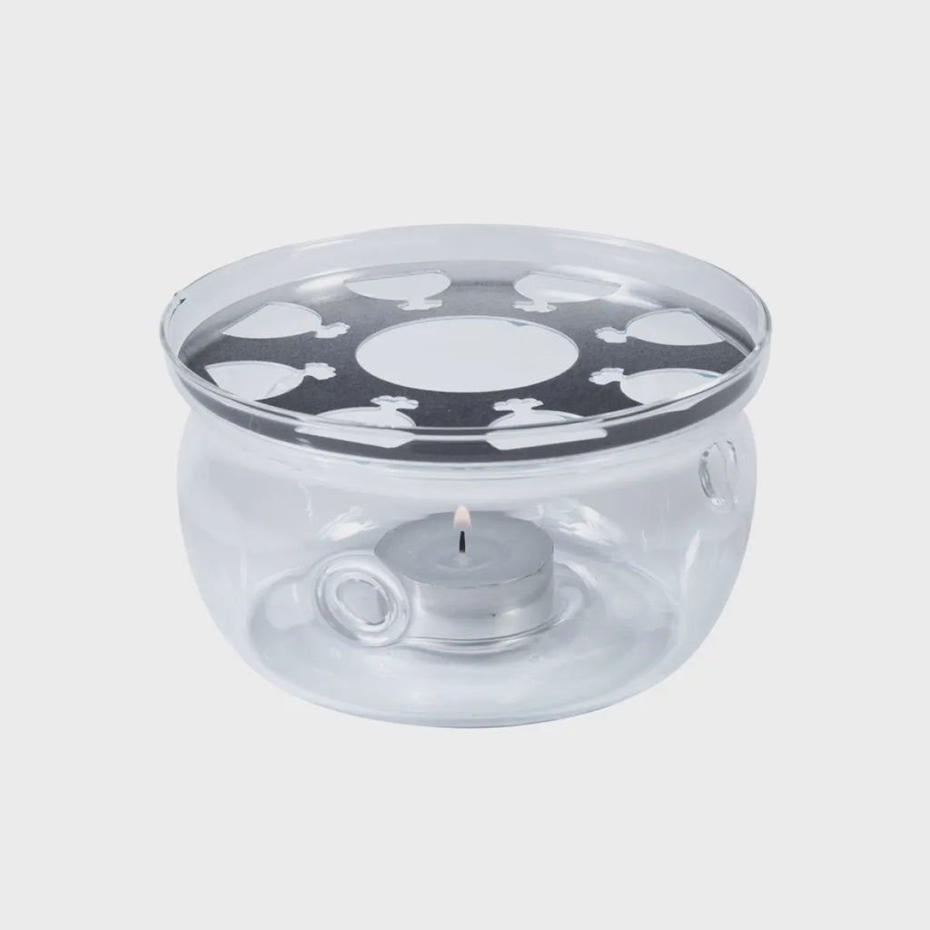 A glass teapot stand with a burner underneath. The stand has a round, flat base.