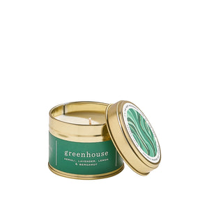 Travel candle in a gold tin with a green lid on a white background