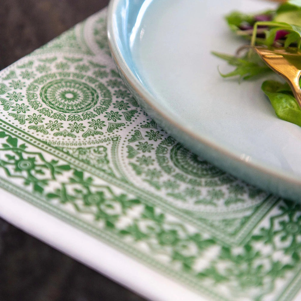 Close-up of a green patterned napkin with a white plate featuring a salad.