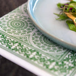 Load image into Gallery viewer, Close-up of a green patterned napkin with a white plate featuring a salad.
