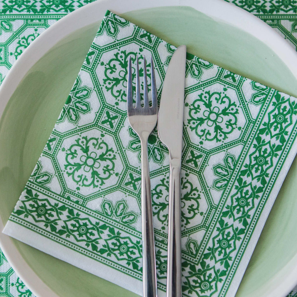 Green and white patterned napkin with a fork and knife on a green plate.