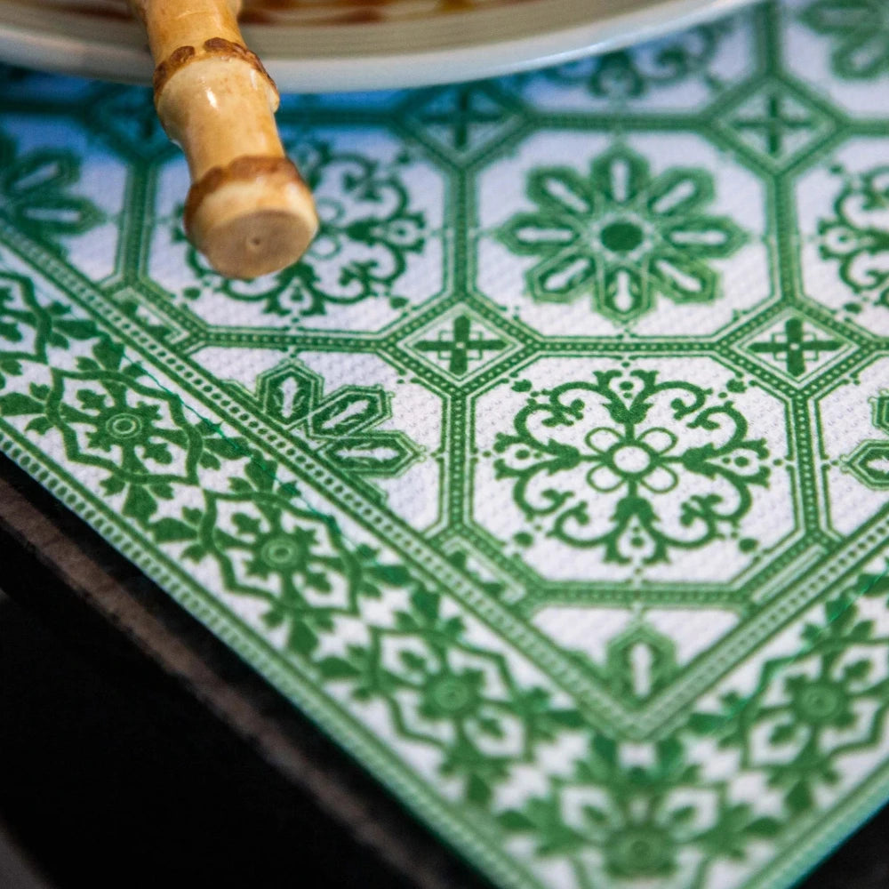 Close-up of a green and white patterned placemat with a wooden object on a dark surface.