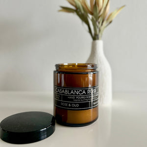 Candle jar labeled 'Casablanca Rose' with a black lid on a neutral background