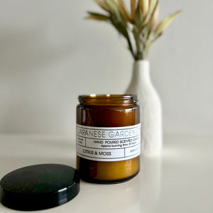 Brown candle jar labeled 'Japanese Garden' with a black lid on a light surface.