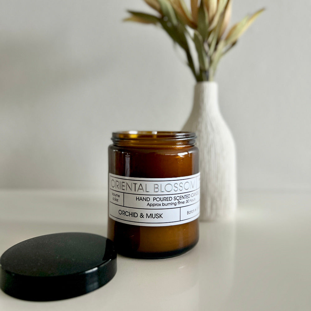 Brown candle labeled 'Oriental Blossom' with a white vase in the background