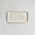 Load image into Gallery viewer, A white ceramic slate with a king protea embossed on the right hand side and gold detailing on the rim. 
