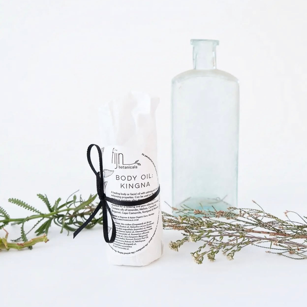 A wrapped bottle filled body oil, labeled 'BODY OIL KINGNA',