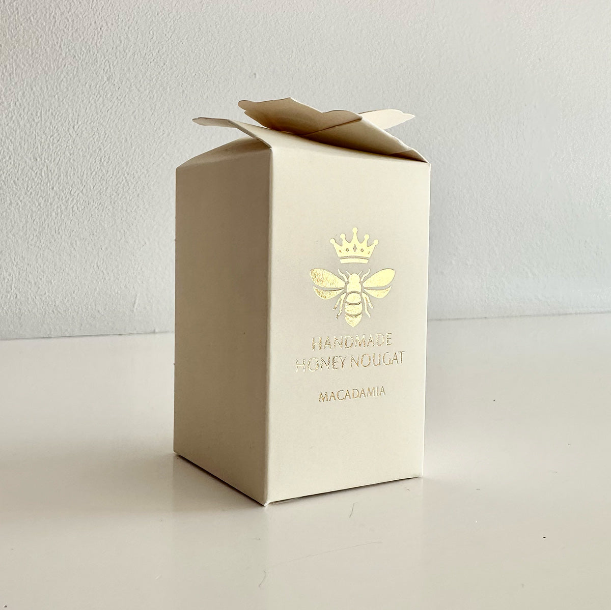 Cream honey nougat box with a gold bee logo and text on a white background
