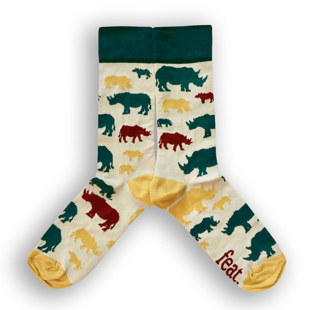 A pair of socks with a cream background featuring silhouettes of rhinos in green, yellow and maroon.