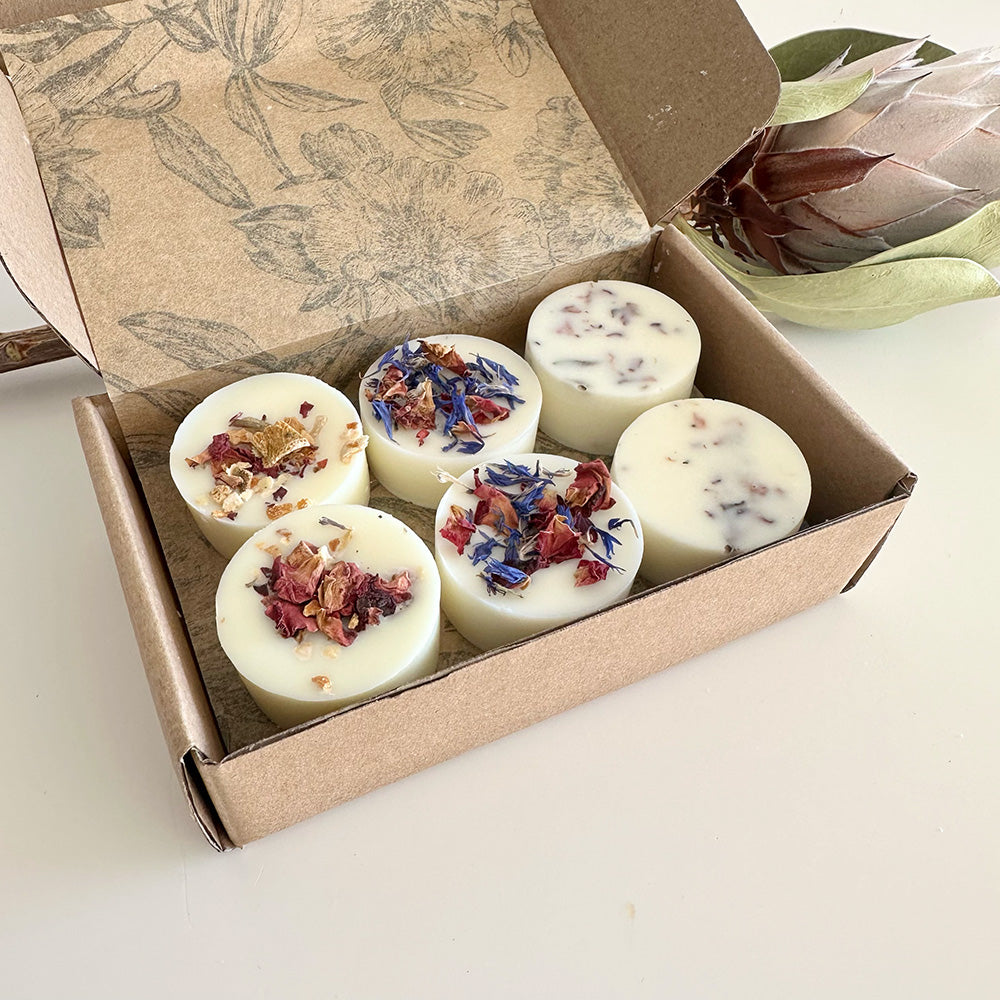 Box of white wax melts with dried flowers on a light background