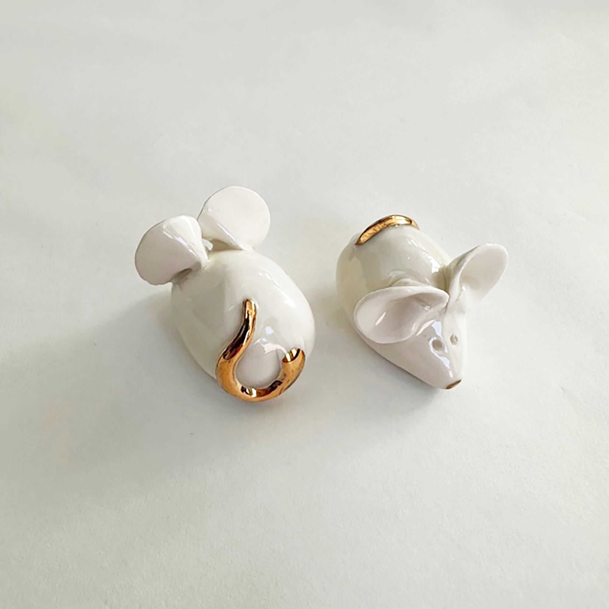 A pair of handcrafted ceramic mice with gold accents displayed on a white background.