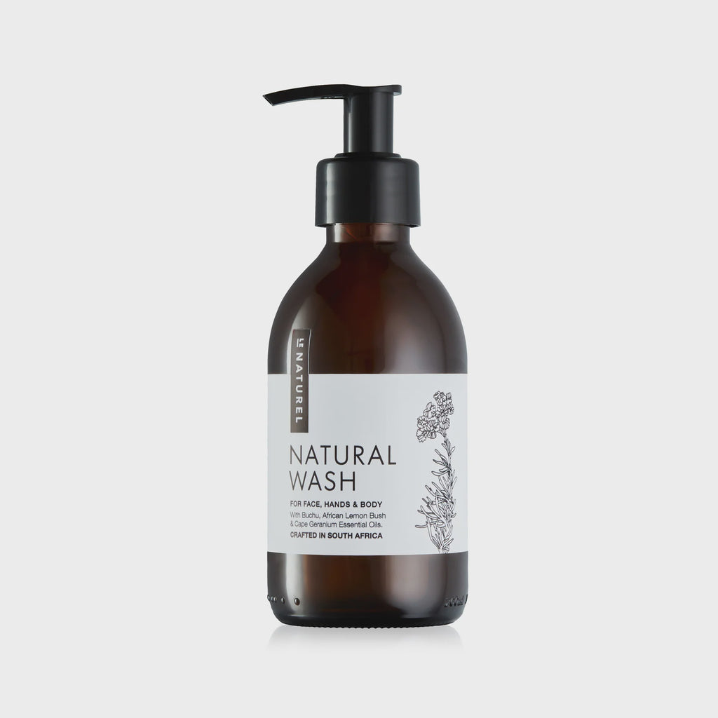 A amber glass bottle with a pump dispenser, labeled 'NATURAL WASH'. The bottle is placed against a white background.