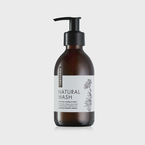 A amber glass bottle with a pump dispenser, labeled 'NATURAL WASH'. The bottle is placed against a white background.