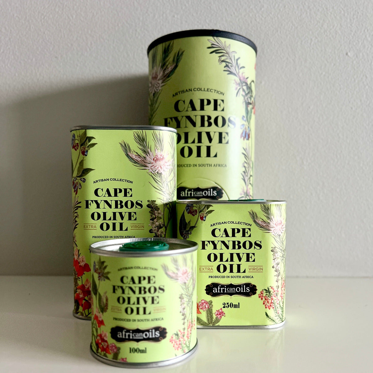 Four tins of Cape Fynbos Olive Oil with decorative labels on a plain background