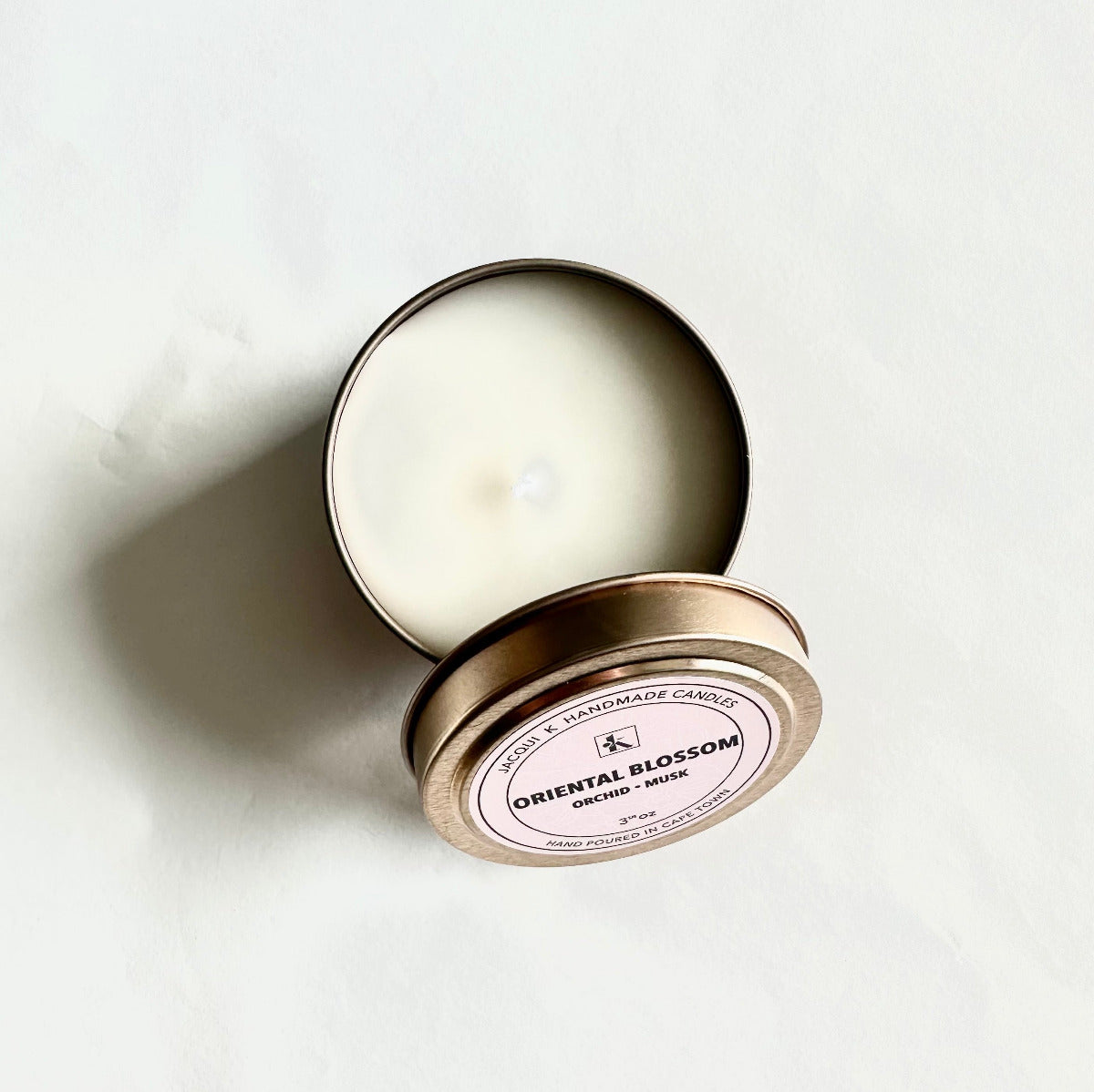 Candle in a tin with 'Oriental Blossom' label on a white background
