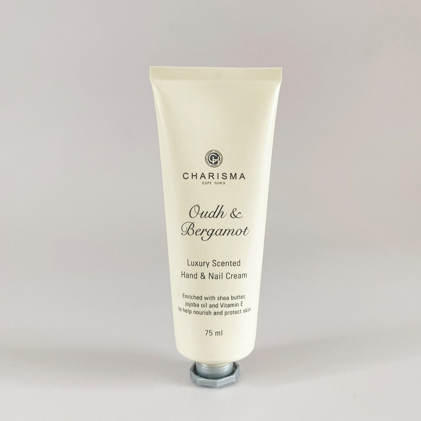 A tube of Charisma brand oud and bergamot luxury hand and nail cream, with the label indicating it is scented with natural essences.