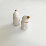 Load image into Gallery viewer, A pair of handcrafted ceramic penguins with gold accents displayed on a white background.
