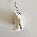 Load image into Gallery viewer, White ceramic penguin decoration on a string against a light gray background
