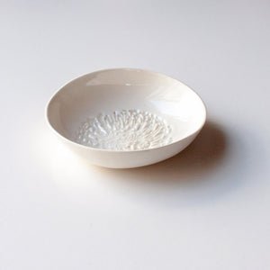 One white ceramic dipping bowl with a pincushion protea motif pressed into the base.