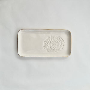 A white ceramic slate with a pincushion protea embossed on the right hand side and gold detailing on the rim. 