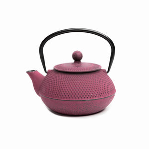 A pink cast iron teapot with a black handle.