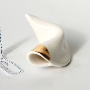 White ceramic fortune cookie with 18 carat gold accent on a light gray background