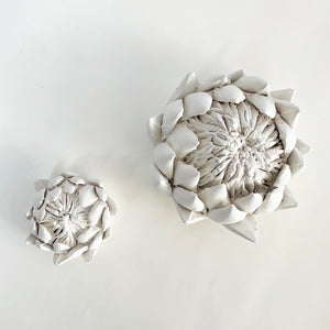 Two bisquewear ceramic protea sculptures on a white background.