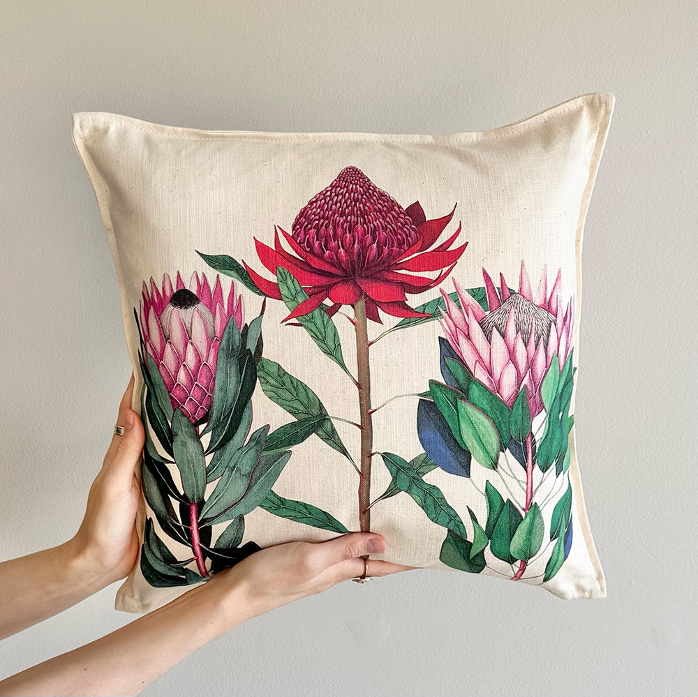 Protea floral-patterned pillow held by a hand against a neutral background