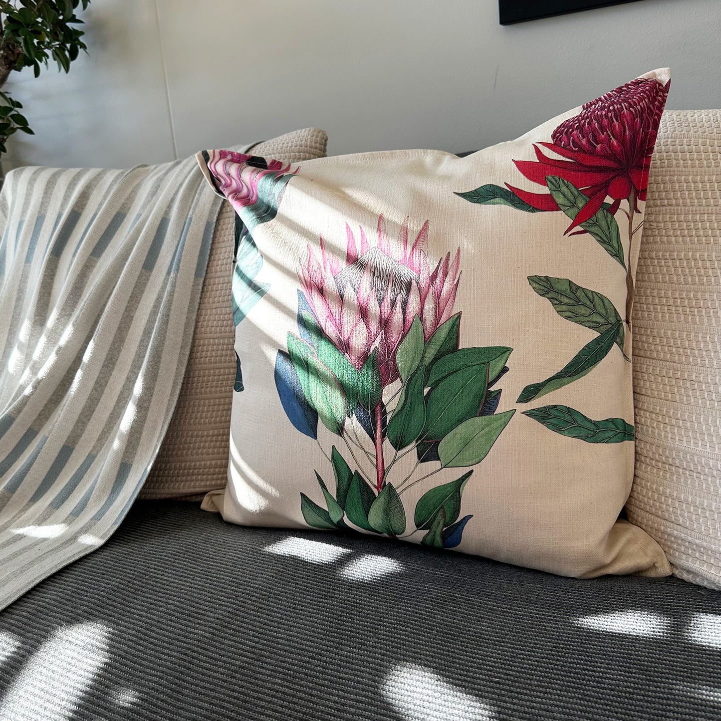 Decorative pillow with protea floral design on a couch