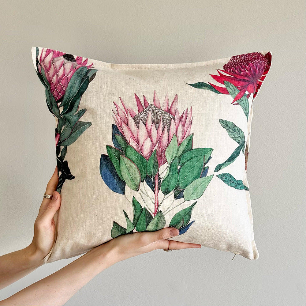Protea floral-patterned pillow held by a person against a neutral background
