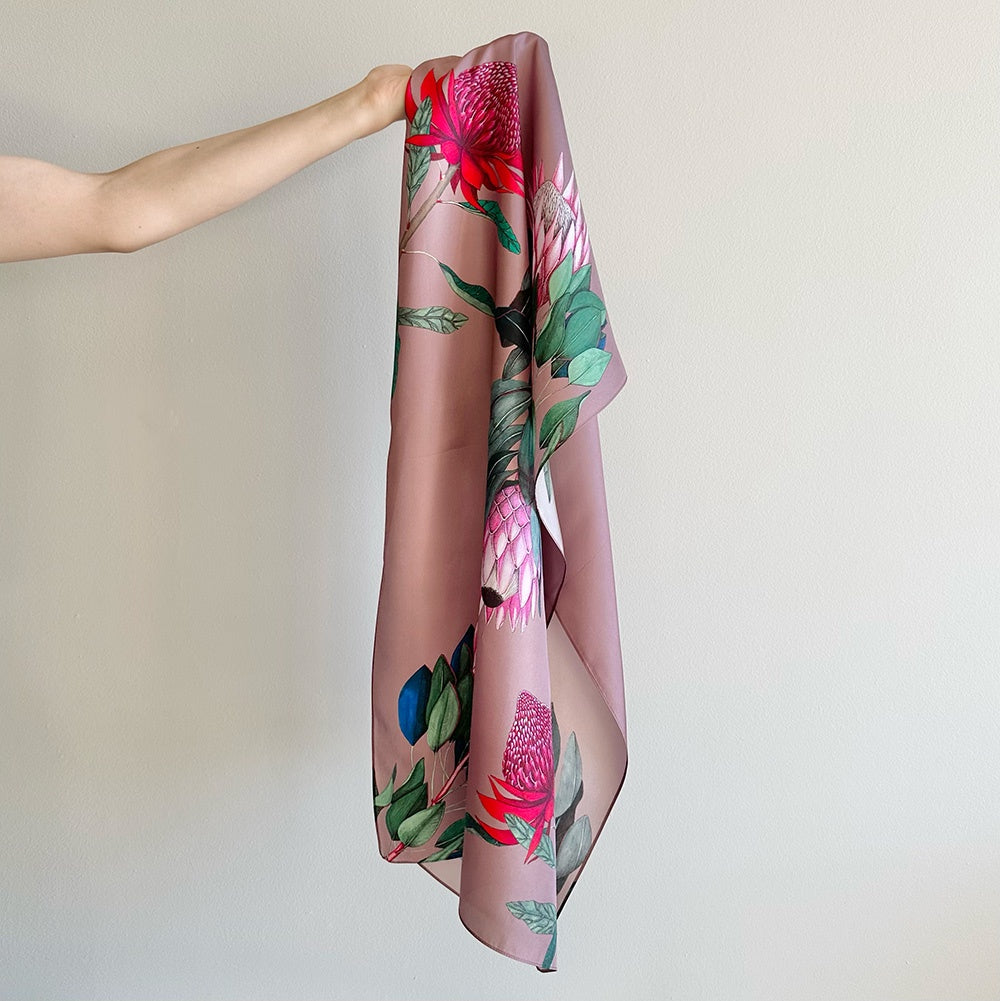Floral-patterned silk scarf held by a person against a plain background