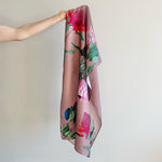 Load image into Gallery viewer, Floral-patterned silk scarf held by a person against a plain background
