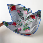 Load image into Gallery viewer, Floral patterned silk scarf held by a hand on a white background
