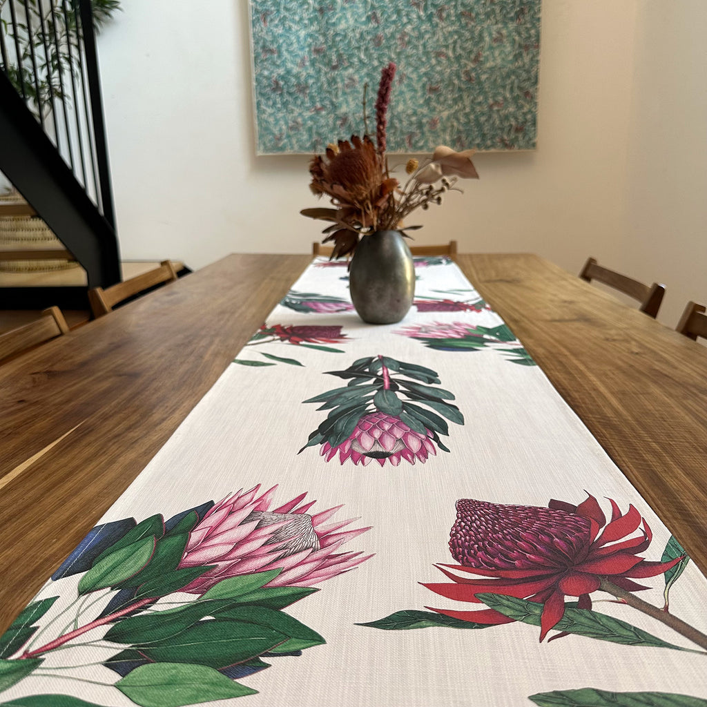 Dining table with a floral table runner and vase of flowers.