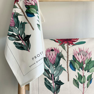 Floral tea towel with protea design hanging on a chair