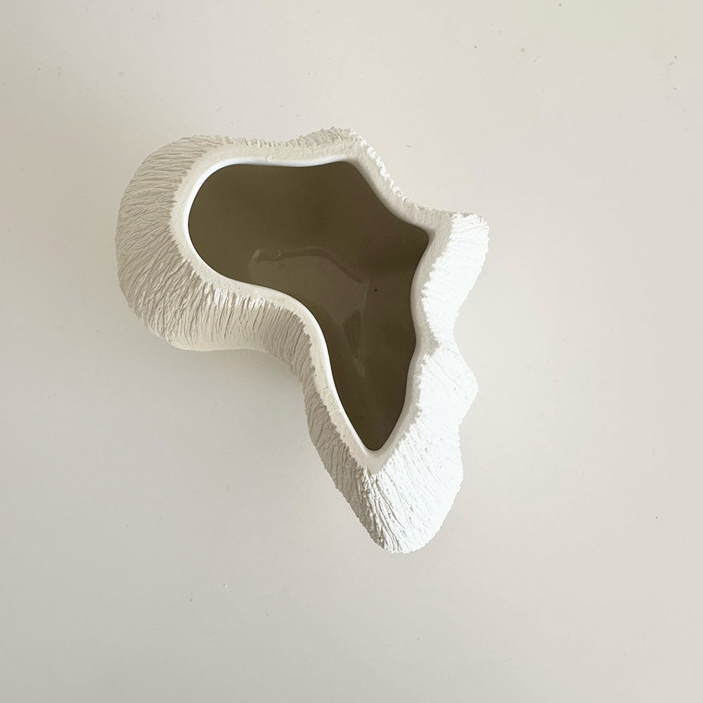 Decorative vase piece with textured surface in the shape of the African continent on a plain background