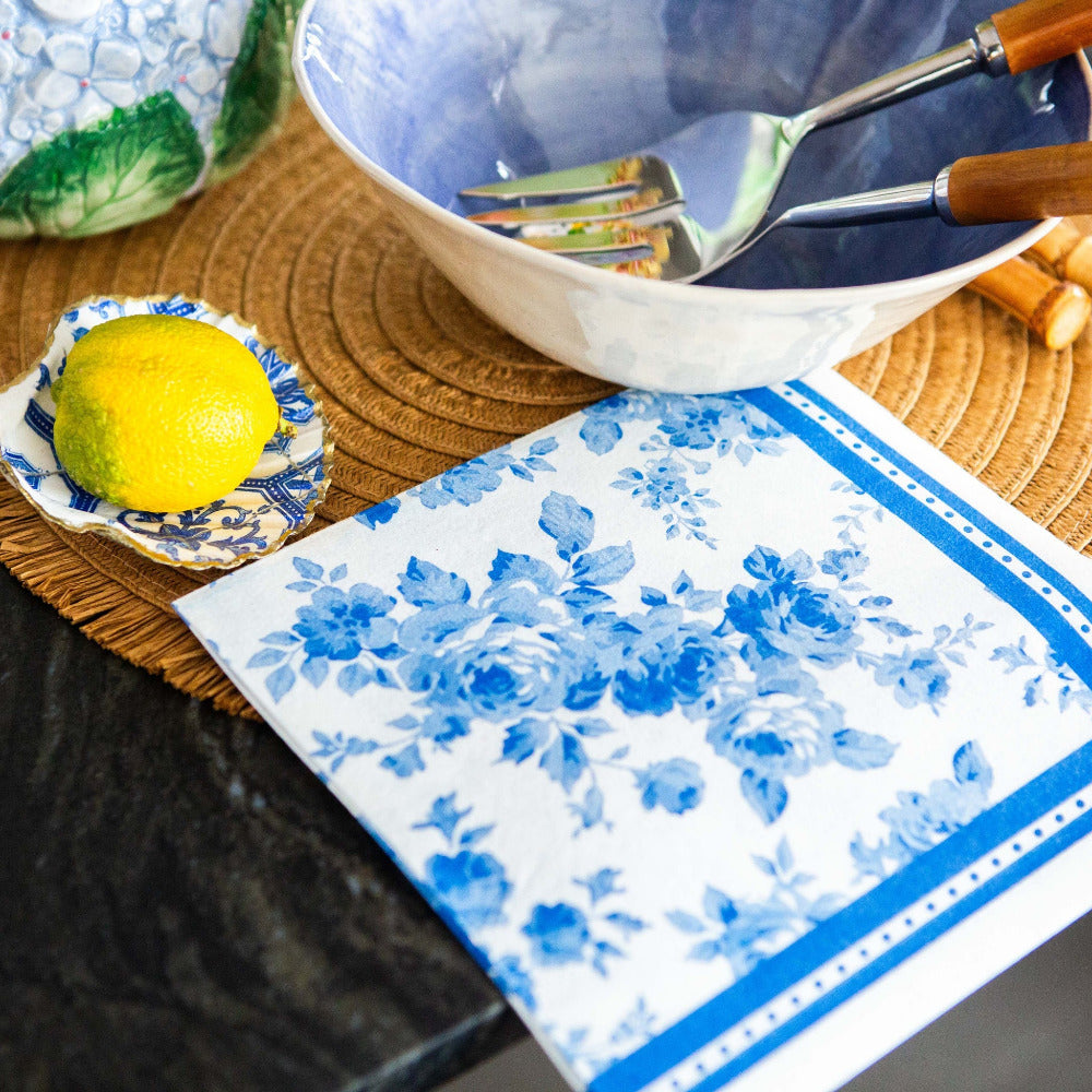 Blue and white floral patterned napkin on a table with a bowl, lemon, and fork.