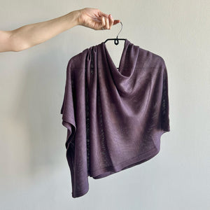 Purple poncho on a hanger against a plain background