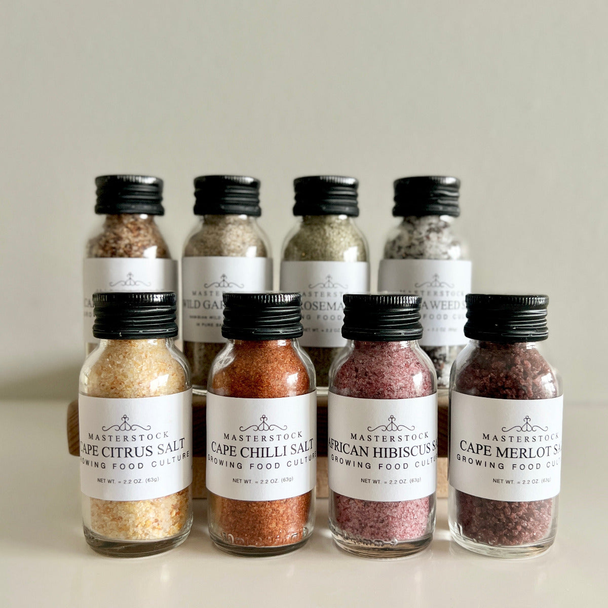 Collection of small bottles of salt with labels on a neutral background
