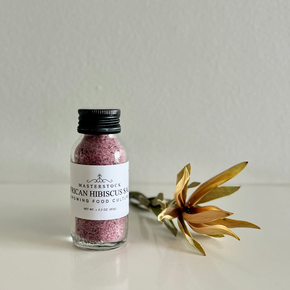 Bottle of Masterstock African Hibiscus Salt with a gold flower on a light background