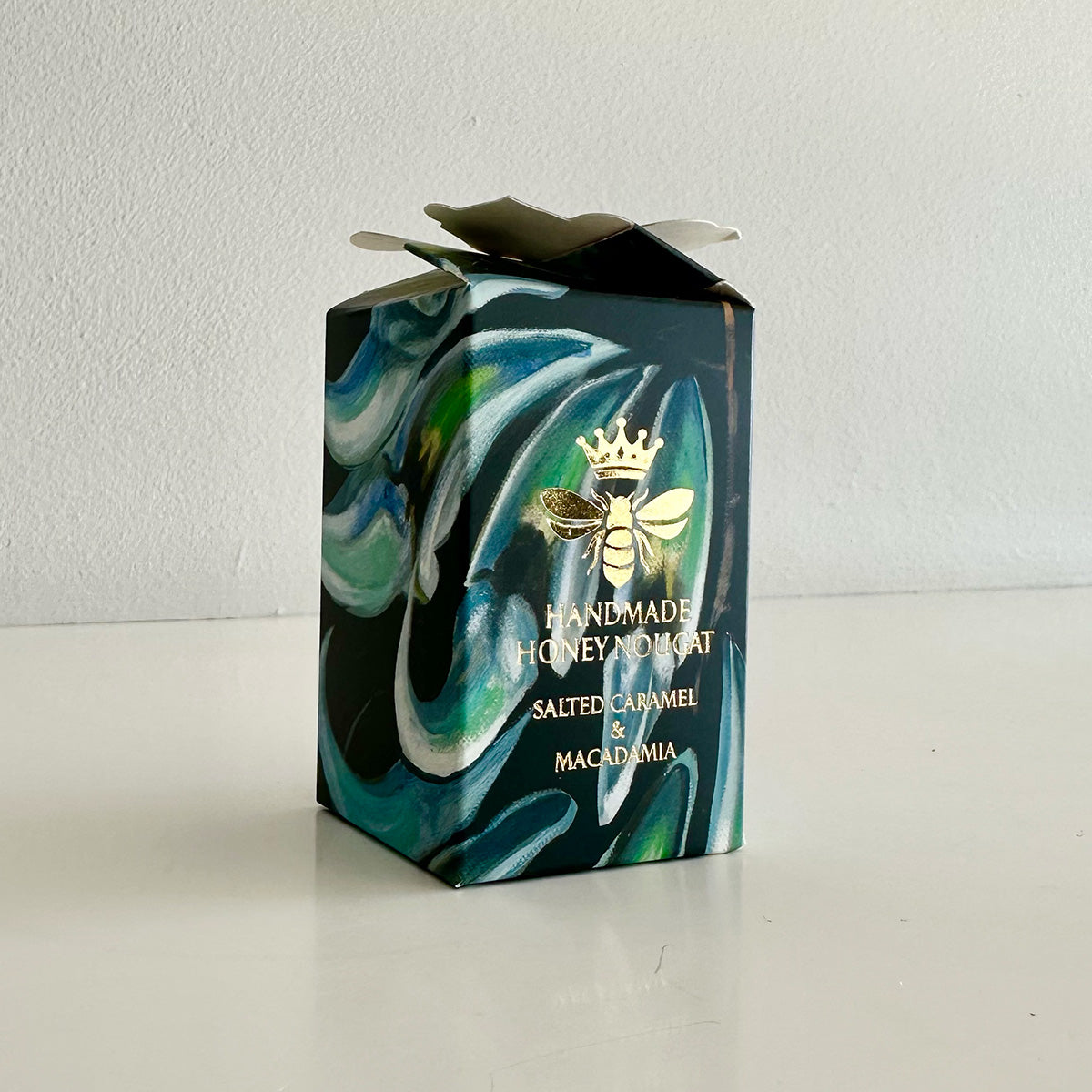 Handmade honey nougat box with marbled design and bee logo on a white background
