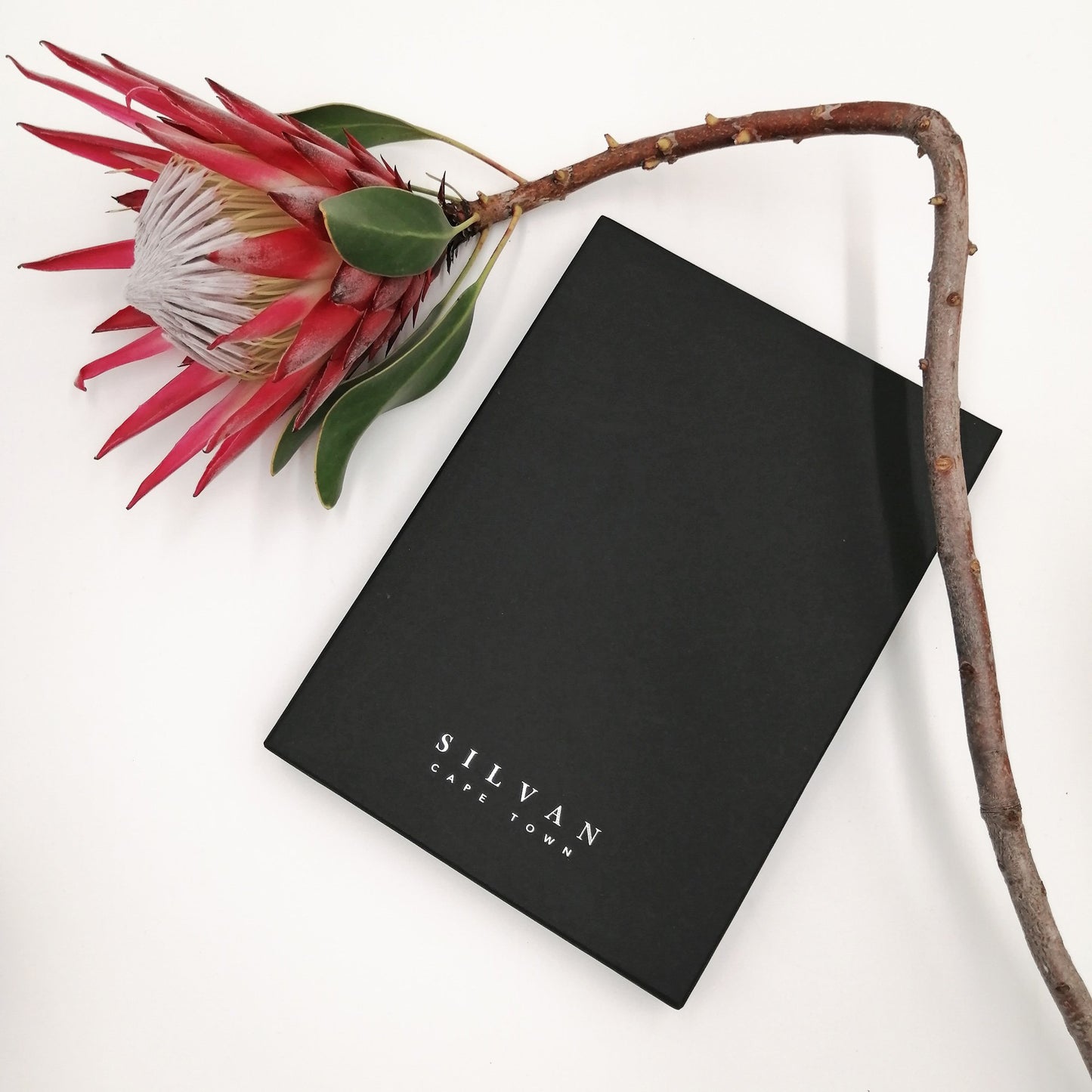 A black scarf box with silver foiled embossed branding.