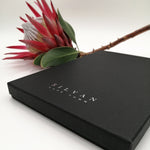 Load image into Gallery viewer, A black scarf box with silver foiled embossed branding.
