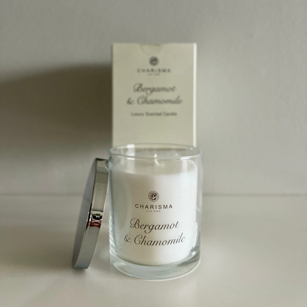 Glass candle with 'Charisma' label and matching box on a light background