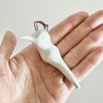 Load image into Gallery viewer, White ceramic bird ornament held in a hand against a light background
